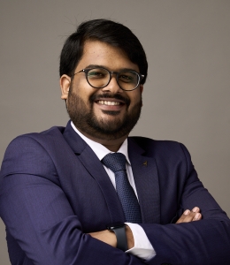 Bearded man with glasses and crossed arms smiling. 