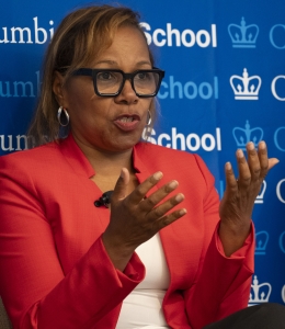 Woman with glasses and red jacket speaking