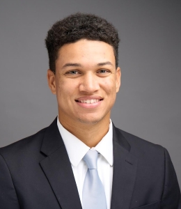 Portrait of Malik Samuels in dark jacket and light blue tie