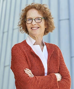 Gillian Lester smiling wearing an orange jacket