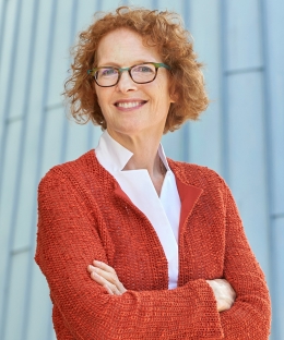 Dean Gillian Lester smiling while wearing an orange jacket