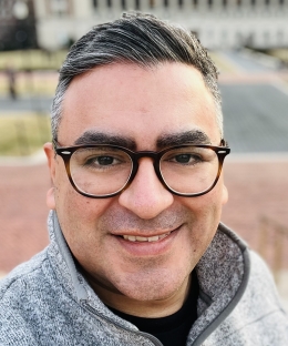 Pictured above is Professor Rodriguez. He has almond shaped brown eyes, tan skin, and straight hair that is combed over to the side. He is wearing glasses and a light grey L.L.Bean quarter zip. 