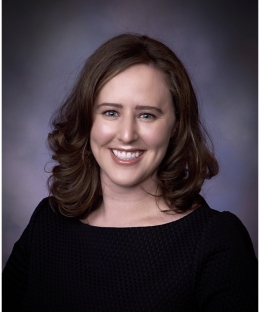 Caitlin McGrail, a smiling white woman with brown hair and a black shirt.