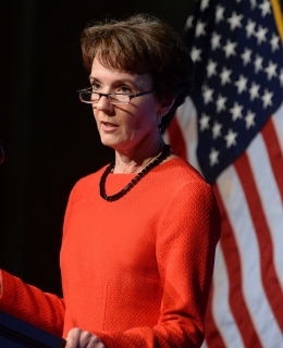 Sarah Cleveland standing at a podium in front of an American flag