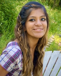 Image of a woman smiling and wearing a multi-colored shirt
