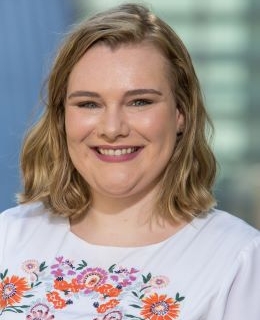 Megan Heatherly wears a white dress with colorful flower embroidery