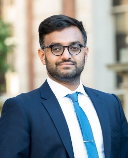 Professor Ashraf Ahmed smiling. He wears glasses with a blue suit and necktie.