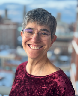Woman in a red shirt and glasses smiling