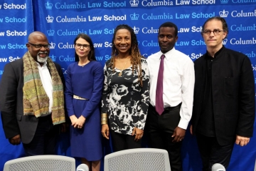 Five Columbia Law professors standing in front of a blue backdrop with the words Columbia Law School repeated many times
