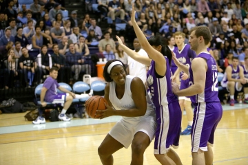 A Columbia Law student holds a basketball while NYU students reach over her.