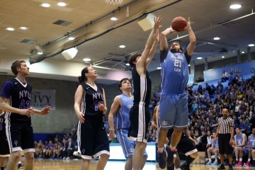 A Columbia Law student jumps to throw a basketball through a hoop.