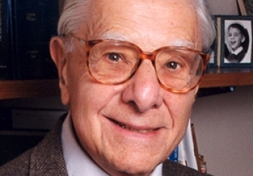 Head shot of man with white hair and glasses