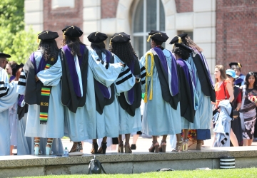 A group of 6 graduates in regalia outside at graduation