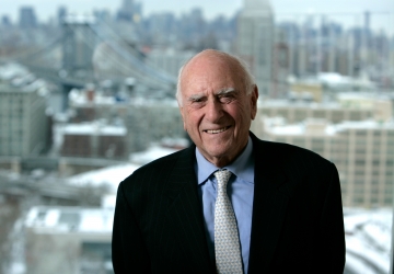 Jack Weinstein portrait, smiling in front of a cityscape