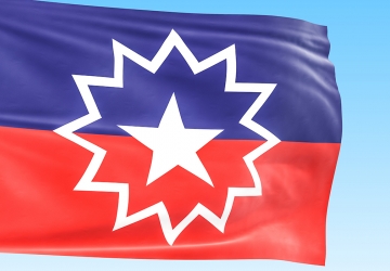 Flag for Juneteenth showing a purple and red stripe and white star inside of a starburst.