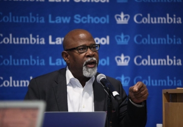 Columbia Law Professor Kendall Thomas in glasses and white shirt in front of mircrophone