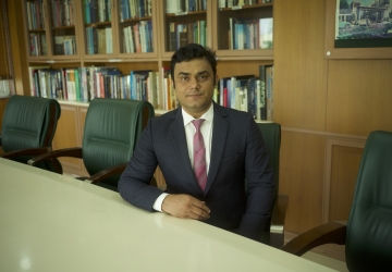 Bhagwati Fellow Devranjan Mishra in suit and tie sitting at conference table