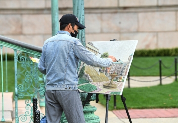 Man in a cap painting outdoors