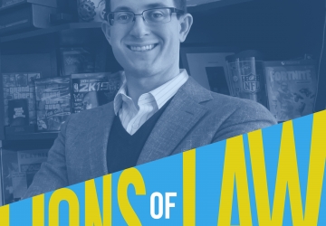 Joshua Simmons in glasses and jacket in front of bookcase with Lions of Law logo at bottom of photograph