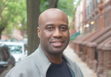 A close-up of multimedia artist Bayeté Ross Smith standing in a New York City street