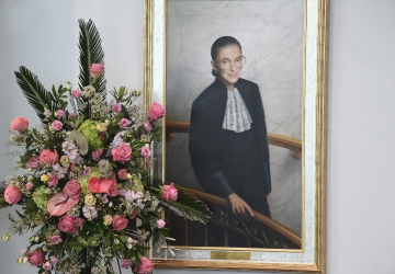 Flowers in front of a portrait of Ruth Bader Ginsburg.