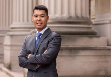 Man with short dark hair in dark great suit and blue tie