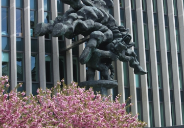 Tree with pink flowers and massive sculpture in front of modern building