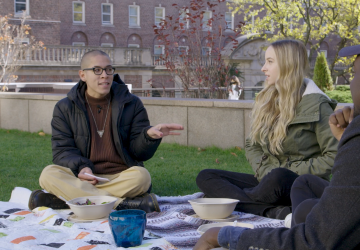 Three students sitting on a lawn talking