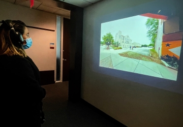 A woman wearing headphones looking at an image on a wall