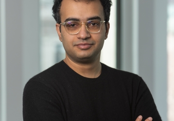 Man in glasses and black sweater with his arms crossed