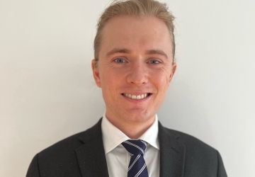 Male student in a suit and blue tie, smiling