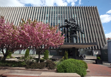 Blooming trees in front of large building and statue