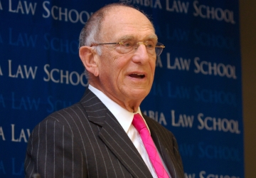 Man with glasses in pinstripe suit and pink tie