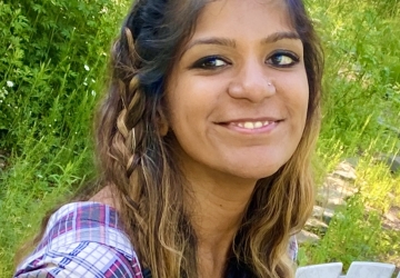 Image of a woman smiling and wearing a multi-colored shirt