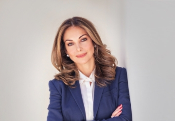 Photo of a woman in a blazer, white shirt, and jeans