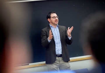 Dark haired man speaking and gesturing 