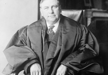 Black and white photo of a man seated wearing justice's robes