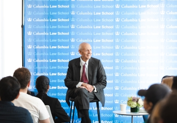 Man in suit in front of Columbia Law School banner