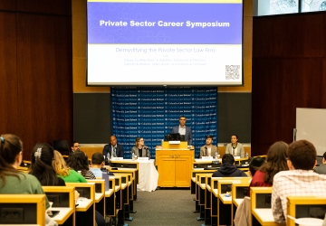 Lecture hall with audience and five person panel in front of room