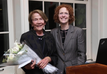 Two women smiling, one with bouquet of flowers