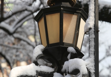 The crown-shaped finial of a wrought iron fence is covered in snow.