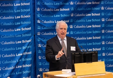 Man in tie at podium in front of Columbia Law School banner