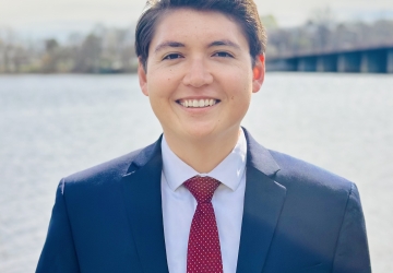 Dark haired man in navy suit with red tie