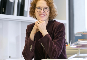 Women with red hair and glasses in her office
