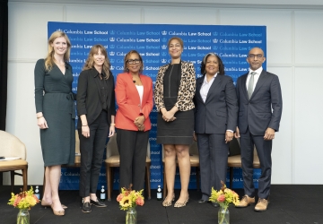 Lineup of five women and a man in professional attire, on a dais.