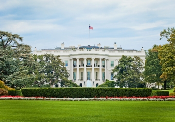 The White House with a blue sky behind and a green lawn in front