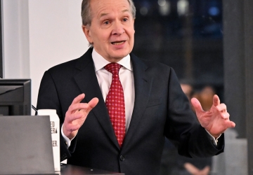 Man in suit and tie gesturing at podium