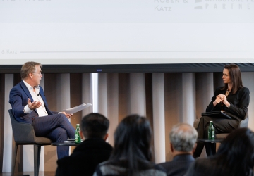Man interviewing woman, both seated onstage