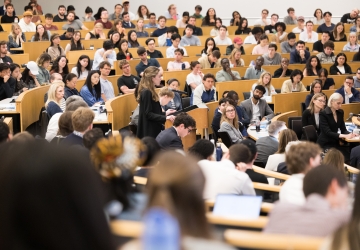 A student at the podium surrounded by fellow students, faculty, and family watching the 2026 Harlan Fiske Stone Moot Court finals.