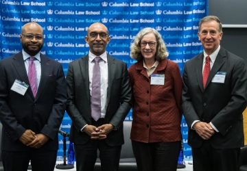 Justice Raheem L. Mullins in suit, Columbia Law Dean Daniel Abebe in suit and tie, Judge Debra Livingston in brick-colored jacket, and Judge Michael A. Chagares in suit and tie all standing in front of a Columbia Law School banner
